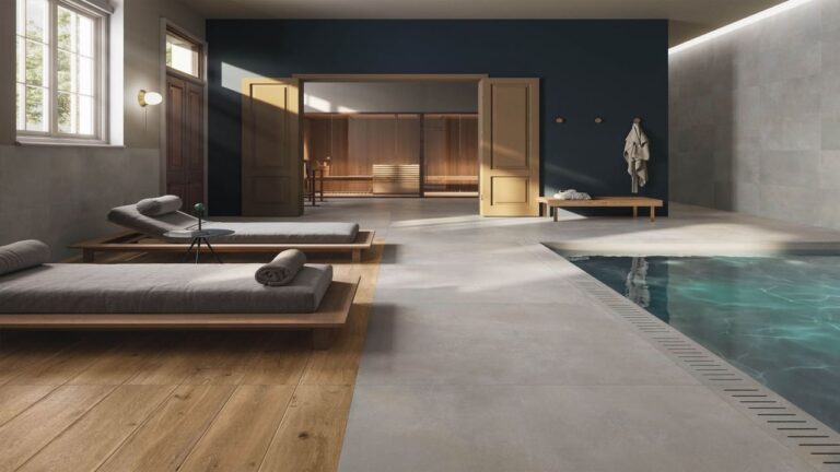 Espace détente intérieur minimaliste avec sol en carrelage effet béton d'Éco Ceramik et piscine intérieure tranquille.