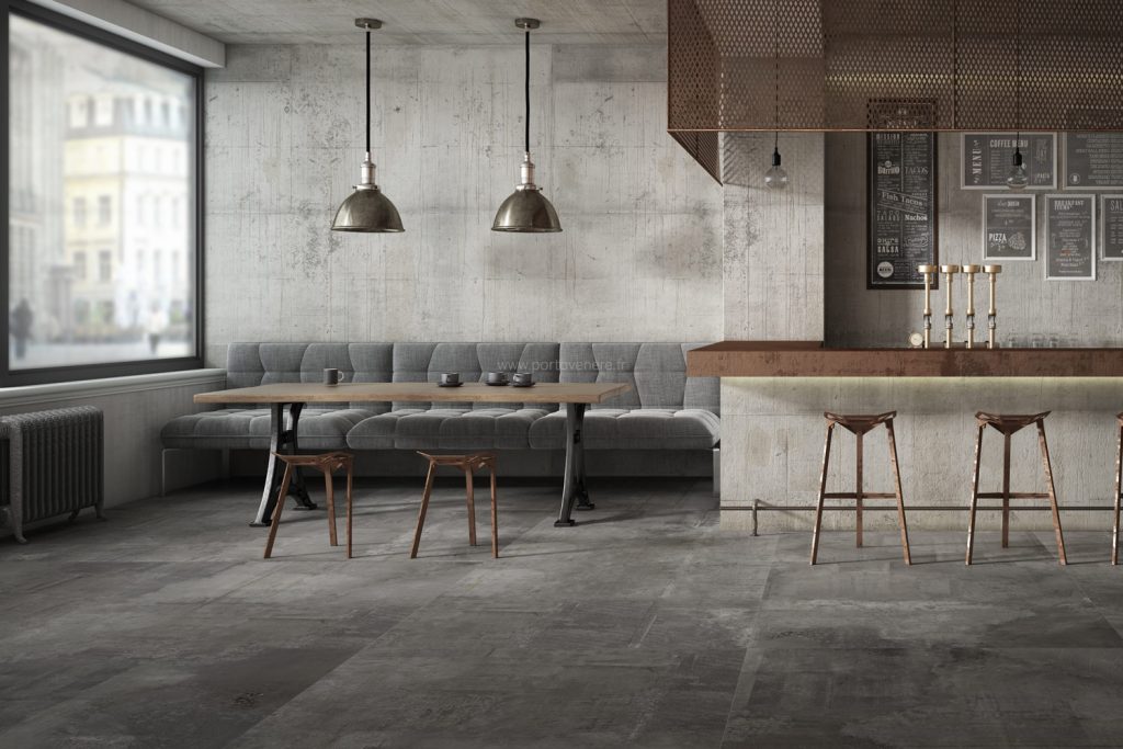 Café au design industriel avec un sol en carrelage effet métal foncé d'Éco Ceramik, complété par des meubles en bois et métal.