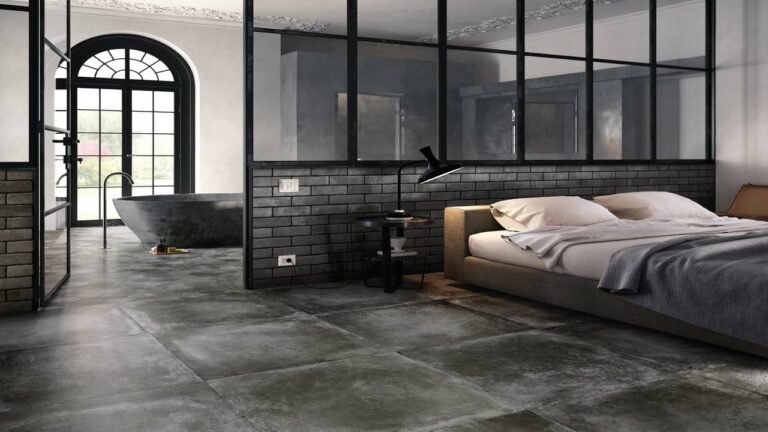 Chambre à coucher élégante avec carrelage effet béton au sol, lit bas contemporain et baignoire autonome dans un espace ouvert.